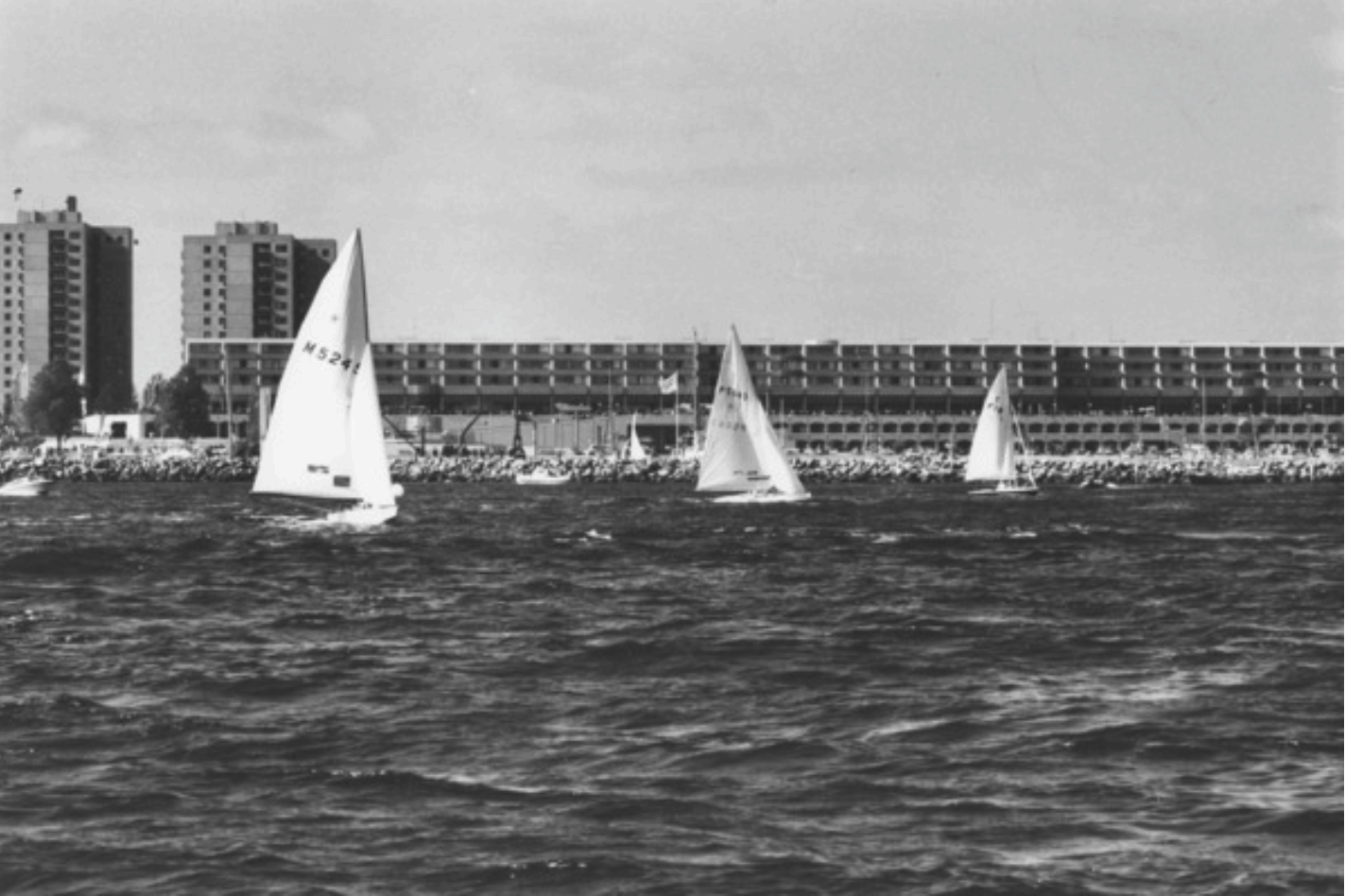 zwei Star-Segelboote und ein Tempest-Segelboot vor dem Olympiazentrum Schilksee; nach Norden segelnd; zwei Motorboote|600